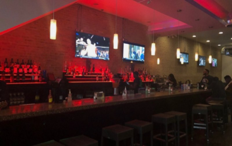 Empty bar stools at illuminated counter.